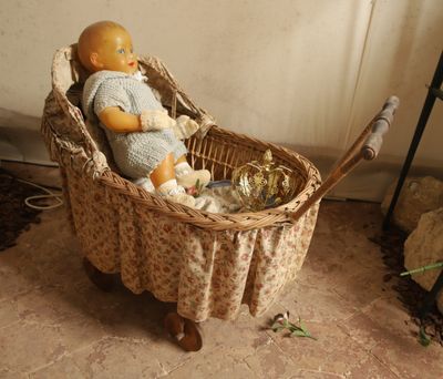 une poupée assise dans un panier contenant une peluche