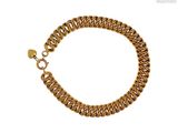 gros plan d'un bracelet en chaîne en or sur fond blanc