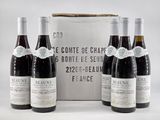 trois bouteilles de vin rouge sont posées devant une boîte de vin