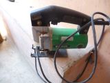 a green and black electric tool sitting on a table