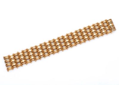 gros plan d'un bracelet en or sur une surface blanche