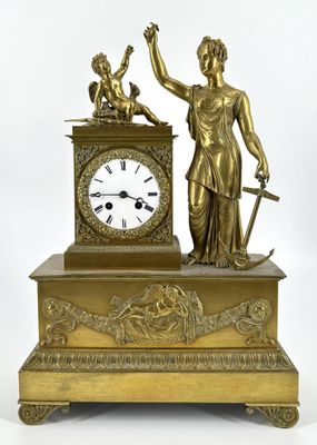 une horloge en or surmontée d'une statue représentant une femme tenant une épée