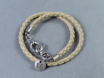 bracelet en cuir orné d'une breloque en argent sur fond gris