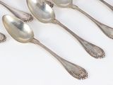 six silver spoons are lined up in a row on a white surface