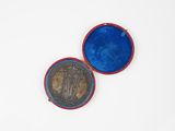 une vieille pièce de monnaie dans un étui bleu posé sur une surface blanche