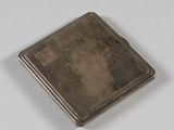 un étui à cigarettes ancien en argent posé sur une surface blanche