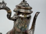 a silver tea pot with a handle on a table