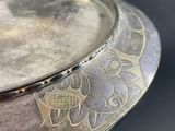 a silver plate with a design on it on a table