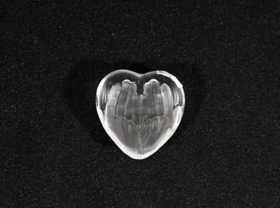 un objet en verre en forme de cœur posé sur une surface noire