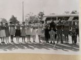 black and white photograph of a group of people standing in front of a bus
