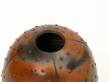 a brown vase with holes on it on a white surface