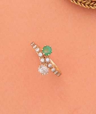 gros plan d'une bague en or avec une pierre verte et des diamants