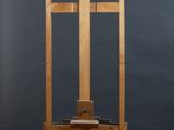 an image of a wooden easel on wheels against a gray wall