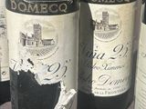 several bottles of wine are lined up on a table in front of a window