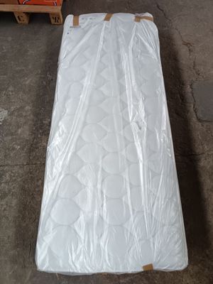 un matelas emballé dans du plastique, posé par terre