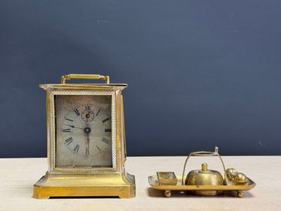 une petite horloge en or et un bateau miniature posés sur une table