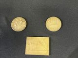 three coins and a small piece of gold on a black cloth