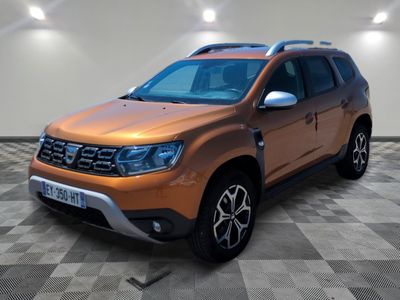 La Dacia orange est garée sur un sol en carrelage à damier.