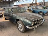an old car is parked in a garage with other cars in the background