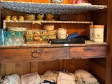 a wooden cabinet with a shelf filled with dishes and cups