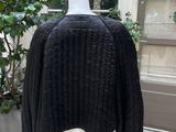 un pull noir posé sur un mannequin devant une vitrine