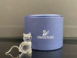 une petite figurine représentant un chat assis à côté d'une boîte bleue