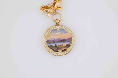 a close up of a gold necklace with a painting on it