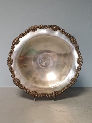 un plat ancien en argent posé sur un socle, sur une table