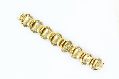 une image d'un gros plan d'un bracelet en or sur une surface blanche