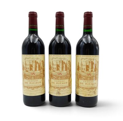 three bottles of red wine sitting next to each other on a white surface