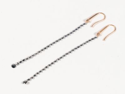 une paire de boucles d'oreilles ornées de diamants noirs sur fond blanc