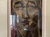 painting of a man ' s face in a white frame on a wall