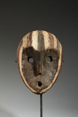 an old wooden mask on a stand on a gray background