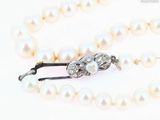 un gros plan sur un collier de perles blanches muni d'un fermoir en argent