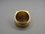 gros plan d'une bague en or sur une surface grise