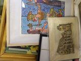 a pile of framed art on a table next to a window