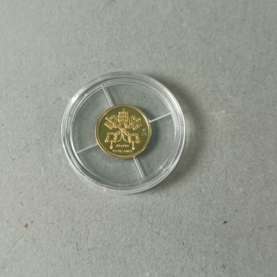 une pièce d'or dans un récipient en plastique transparent posé sur une table