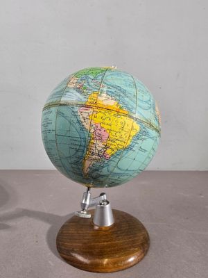 un petit globe posé sur un socle en bois, sur une table