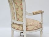 an old chair with a floral upholstered seat and arm rest