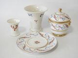a white table with a bowl, plate, and cups