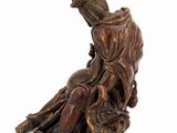 an image of a wooden statue of a woman sitting on a rock