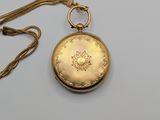 a gold pocket watch with a chain on a white surface