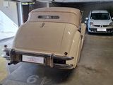 a tan car parked in a garage next to a white car