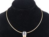 un collier en or orné d'une perle de verre autour du cou d'un mannequin