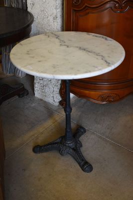 a marble table with a black base and a wooden cabinet in the background