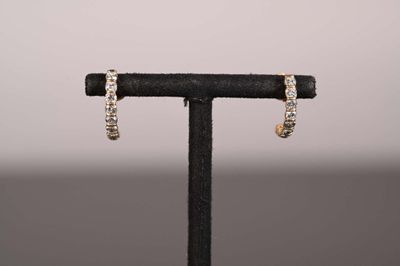 une paire de boucles d'oreilles créoles en diamant posées sur un présentoir noir