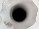 a white vase with a black hole in it