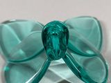 green glass butterfly on a white plate sitting on a table