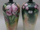 two vases with flowers painted on them sitting on a table