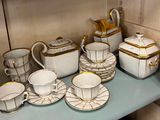a lot of white and gold dishes and cups on a shelf